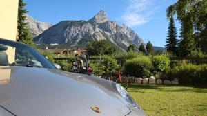 un coche aparcado en un patio con una montaña en el fondo en Hotel Alpin en Ehrwald