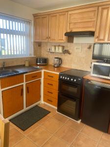 una cocina con armarios de madera y estufa negra en Trudora en Tintagel