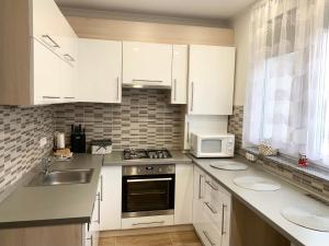 een keuken met witte kasten, een spoelbak en een magnetron bij Modern two bedroom flat with balcony in Lenti +14 foto's