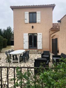 um pátio com uma mesa e cadeiras em frente a uma casa em AU MIMOSA -Gîte Le Canigou em Passa