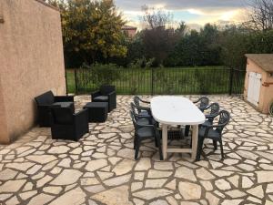 um pátio de pedra com uma mesa branca e cadeiras em AU MIMOSA -Gîte Le Canigou em Passa