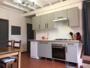 uma cozinha com armários brancos e um forno com placa de fogão em AU MIMOSA -Gîte Le Canigou em Passa
