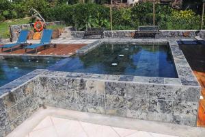 a swimming pool with a stone retaining wall and a stone patio at Residence Foulsafat in Rodrigues Island