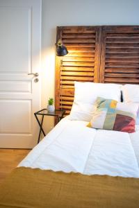 a bed with white sheets and a wooden headboard at Charmant 2 pièces in Poissy