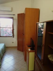 a bedroom with a bed and a television and a window at Monolocale a 200 metri dal mare in Funtana Meiga