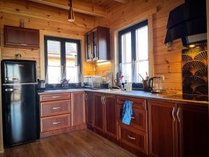 a kitchen with wooden cabinets and a black refrigerator at Świerkowy Domek pod Aniołem in Łapy