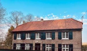 uma casa de tijolos com telhado vermelho e janelas brancas em Casa WaMü Nature Reserve direkt am Altrhein em Xanten