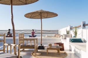 a patio with a table and chairs and an umbrella at SwellHouse in Tamraght Ouzdar
