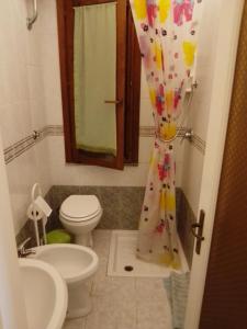 a bathroom with a toilet and a shower curtain at Monolocale a 200 metri dal mare in Funtana Meiga