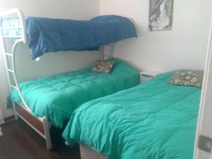 1 dormitorio con 2 literas con sábanas verdes en Departamento en Condominio Mar Serena, en La Serena