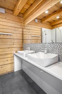 uma casa de banho com 2 lavatórios e uma parede de madeira em Bajkowe Domki em Kudowa-Zdrój