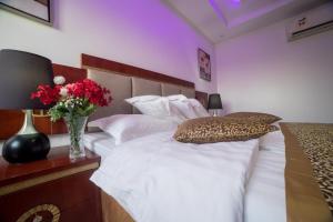 شقق مفروشة مميزة - hotel apartments for rent في جدة: غرفة نوم بسرير ابيض مع إناء من الزهور
