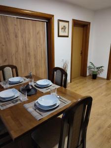 una mesa de madera con sillas y platos. en Apartman Adna, en Kulen Vakuf