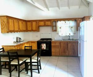 een keuken met houten kasten, een tafel en een koelkast bij Bay View Apartment 4 - Canouan Island in Canouan