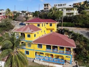 een geel huis met een rood dak bij Bay View Apartment 4 - Canouan Island in Canouan