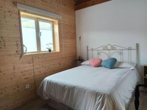 1 dormitorio con 1 cama blanca y 2 almohadas en Casa de madera El jardín de Tara, en Tiñor
