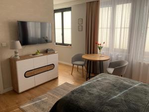 Schlafzimmer mit einem Bett, einem TV und einem Tisch in der Unterkunft Apartament Perłowy in Zamość