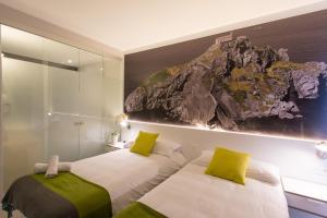畢爾包的住宿－畢爾巴奧城市客房酒店，卧室内的两张床,墙上有绘画作品