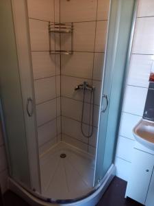 una ducha con una puerta de cristal junto a un lavabo en Hotel RÓŻA, en Łosice