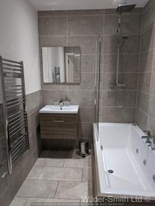 a bathroom with a tub and a sink and a shower at Stylish 2-Bed Luxury Apartment in Nottingham City in Nottingham