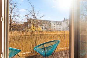 ミュンヘンにあるFlatista Homes - Hirschgartenのフェンス付きのバルコニーに青い椅子2脚