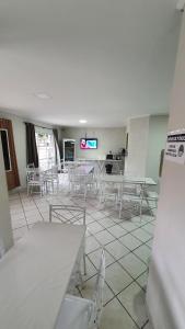 a room with white tables and chairs and a tv at ACM Hotel in Aluminio