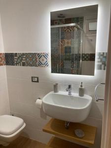a bathroom with a sink and a toilet and a mirror at Casa Vacanze al Trenta3 in Marsala