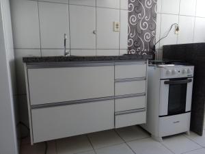 uma cozinha com armários brancos e um fogão em Apartamento proximo ao shopping Franca em Franca
