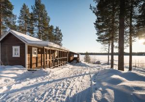 a cabin in the snow next to a lake at Sandsjögården Holiday Resort in Blattniksele