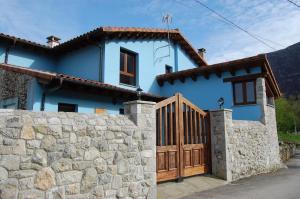 a blue house with a stone wall and a wooden gate at Vivienda Vacacional El Refugio in Llanes