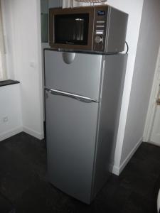 Un four micro-ondes est installé au-dessus d'un réfrigérateur. dans l'établissement Appart-Hotel T1 Lyon8 proche hopitaux, à Lyon