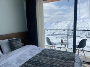 - une chambre avec un lit et une vue sur les montagnes enneigées dans l'établissement gudauri amazing mountain view, à Goudaouri