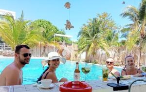 a group of people sitting at a table by a pool at Beach Houses in Rawai Beach +19 photos