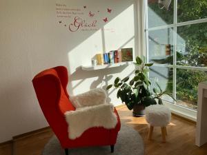 a red chair with two white stuffed animals in a room at Ferienwohnung Traumreich in Bad Harzburg
