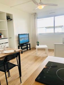 een woonkamer met een tafel en een televisie bij Superbe appartement front de mer in Villeneuve-Loubet