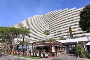 een groot wit gebouw met een winkel ervoor bij Superbe appartement front de mer in Villeneuve-Loubet