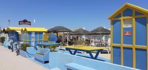 ein blaues und gelbes Gebäude mit Tischen und Sonnenschirmen in der Unterkunft Hotel Garden B&B in Marotta