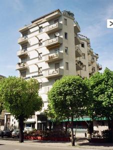 un edificio alto y blanco con árboles delante en Hotel Engadina, en Como