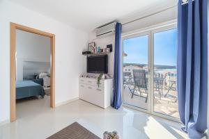 een woonkamer met een televisie en een balkon bij Luka's SEA View Terrace & Steps from the Beach apartment in Mirce
