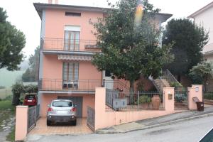 a car parked in front of a pink house at B&B Da Roby in Corinaldo
