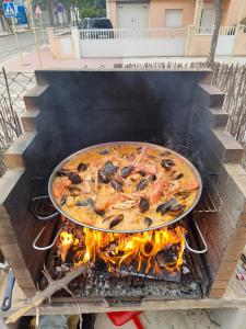 a pizza on top of a grill with flames at Can Kuqueta, Platja d'Aro in Platja  d'Aro