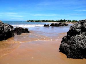 a beach with black rocks and the ocean at Les Hirondelles in Ngaparou