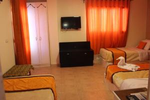 a room with two beds and a television and a duck on a chair at Osiris Hotel Cairo in Cairo