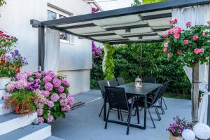eine Terrasse mit einem schwarzen Tisch, Stühlen und Blumen in der Unterkunft Modern apartment with an outdoor jacuzzi in Brodarica