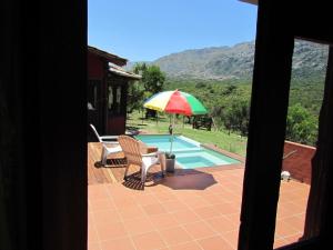 a patio with a chair and an umbrella next to a pool at Cabañas San Miguel in Cortaderas