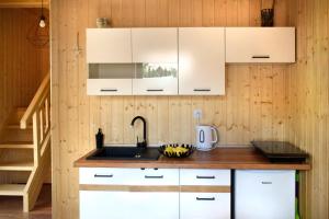 kuchnia z białymi szafkami i zlewem w obiekcie Nadmorskie Klimaty - Domki Całoroczne w Stegnie