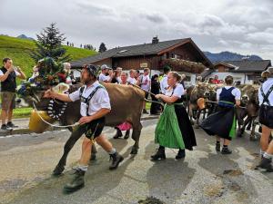 a group of people walking a cow down a street at Ferienwohnung Alpenherz in Obermaiselstein