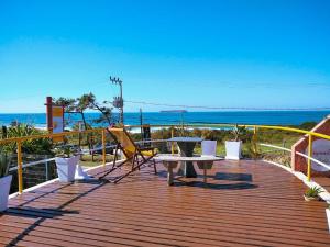 a wooden deck with a table and chairs on the beach at Pousada Bangalôs Da Mole - Florianópolis in Florianópolis