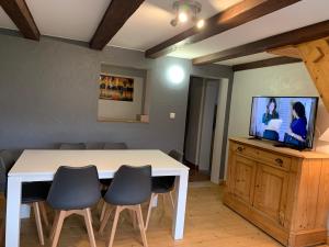 una camera con tavolo e sedie bianchi e TV di Gîte de Juliana 6 personnes a Sundhouse
