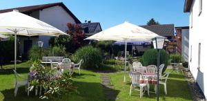 a yard with tables and chairs and umbrellas at Hotel & Restaurant Eichholz in Kassel